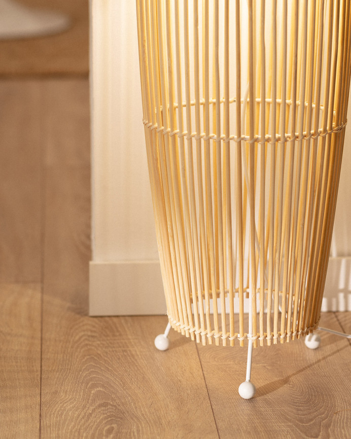 Lampadaire composé d'une base en métal blanc et de branches de bambou reliées par une tresse de fibres naturels