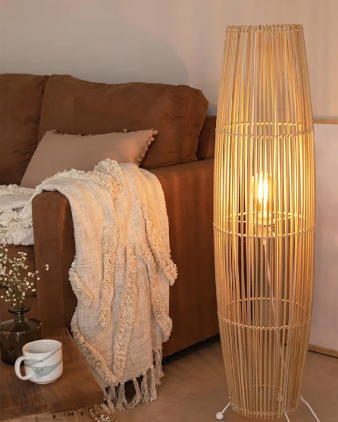Lampadaire composé d'une base en métal blanc et de branches de bambou reliées par une tresse de fibres naturels