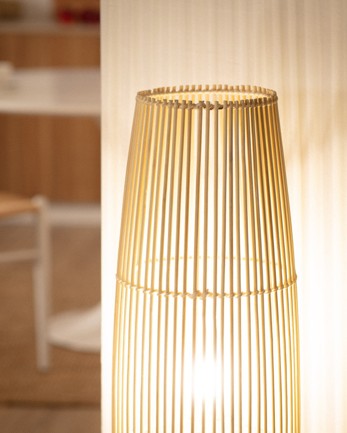 Lampadaire composé d'une base en métal blanc et de branches de bambou reliées par une tresse de fibres naturels